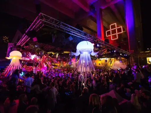 En livlig nattklubb i Stockholm med uppblåsbara maneter, discokulor och en stor publik som dansar under neonljus.