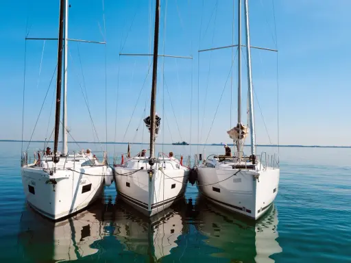 Drei weiße Segelyachten liegen nebeneinander im ruhigen Wasser. Ein Blick auf die elegante Bauweise, wie sie nur ein renommierter segelyacht hersteller hervorbringen kann.