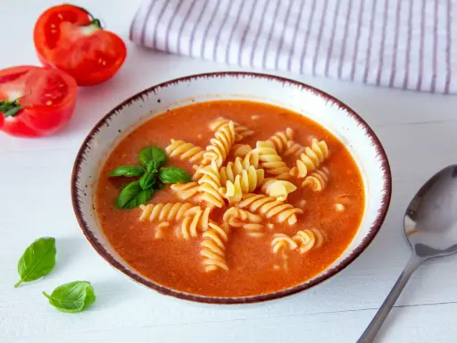 Zupa pomidorowa z makaronem fusilli, świeżą bazylią i pomidorami. Idealne jakie przyprawy do zupy pomidorowej? Bazylia i czosnek!