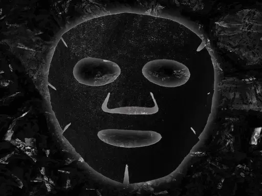 Maschera al carbone, con i suoi benefici, appare come un volto misterioso incorniciato da texture scure e profonde.