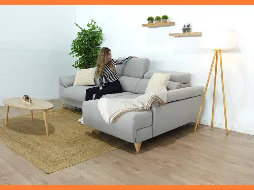 Mujer colocando cojines en chaise longue gris. Un estilo acogedor para tu salón.