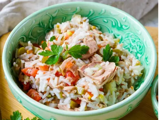 Schüssel mit Reissalat mit Thunfisch, Tomaten, Gurken und Petersilie. Ein leckeres und einfaches Gericht.