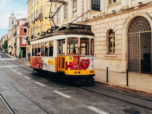 Gelbes Tram fährt durch Lissabon. Perfekt für eine Erkundungstour beim Lissabon wandern.