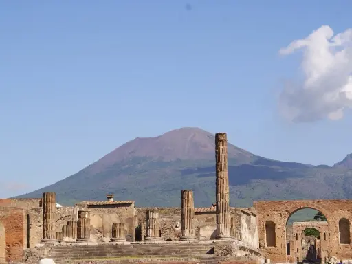 Rovine di Pompei con il Vesuvio sullo sfondo. Un'idea per cosa visitare a Pompei in un giorno, tra colonne antiche e storia millenaria.