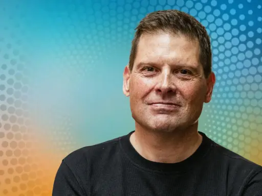 Porträt eines Mannes mit freundlichem Lächeln vor einem bunten Hintergrund. Man fragt sich, was macht Jan Ullrich heute?