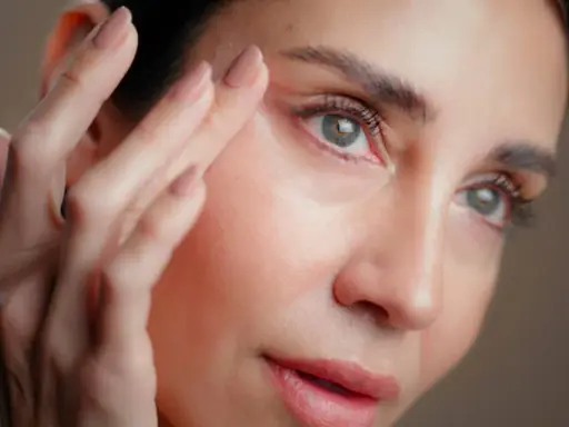 Une femme applique un soin sur son visage. Attention, l'acide hyaluronique peut parfois assécher la peau si mal utilisé.
