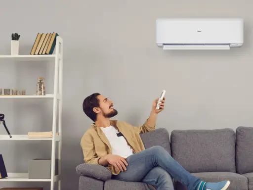 Uomo sorride usando telecomando per accendere un cool condizionatore. Il suo significato è comfort e benessere in casa.