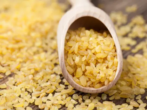 Kasza bulgur na drewnianej łyżce. Niska kasza bulgur indeks glikemiczny sprawia, że jest idealna dla diabetyków.
