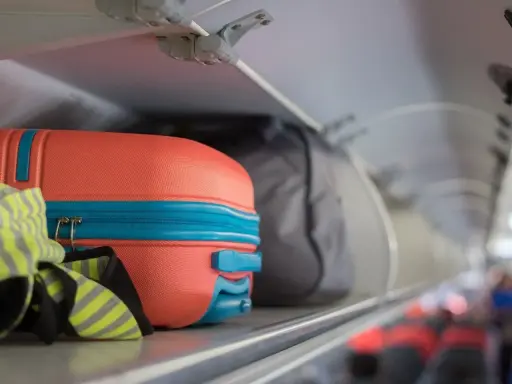 Pomarańczowa walizka i szara torba jako flydubai bagaż podręczny w schowku nad siedzeniami.