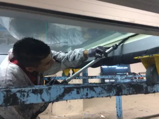 Un trabajador aplica **silicona estructural** en una junta de ventana.