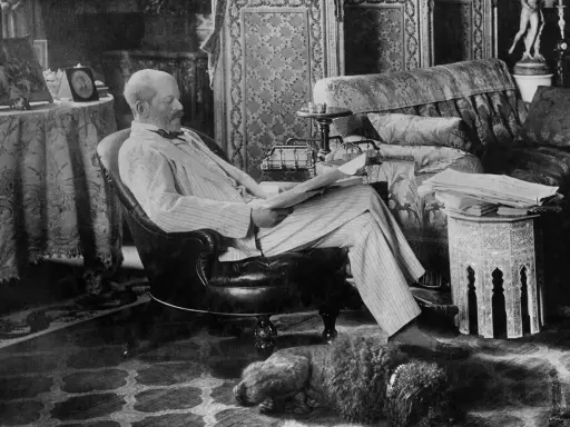 A man reads in a plush armchair, a dog sleeps nearby. The opulent room hints at the grandeur of the Rothschild art collection.