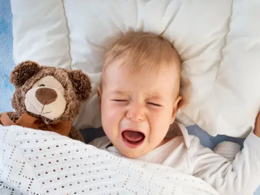 Bebé llorando en la cama con su osito de peluche. Mi hijo de 2 años se despierta mucho por la noche.