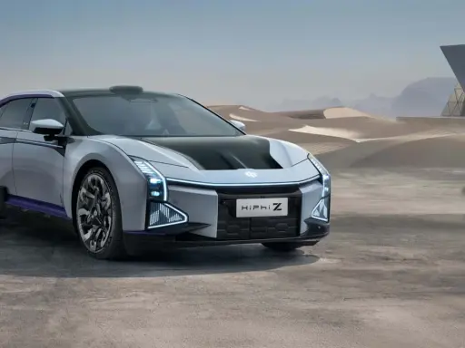 Futuristisches Elektroauto HiPhi Z in silber mit lila Akzenten, steht in einer Wüstenlandschaft vor einer modernen Glasarchitektur.