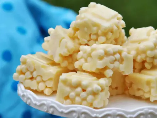 Leckere zuckerfrei leben rezepte: weiße Schokoladenstücke mit knusprigen Reispops auf einem weißen Teller.
