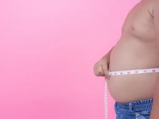 Mężczyzna mierzy swój duży brzuch. Miarka pokazuje ponad 37 cm.