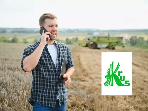 Rolnik rozmawia przez telefon na polu, planując, jak założyć firmę na krusie. W tle kombajn zbiera plony.