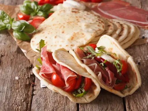 Piadina romagnola, un piatto tipico di Rimini, farcita con prosciutto crudo, pomodorini e rucola.