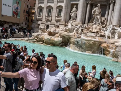 Foule de touristes admirant la fontaine de Trevi, la fontaine de l'amour à Rome, prenant des selfies devant les statues majestueuses et l'eau turquoise.