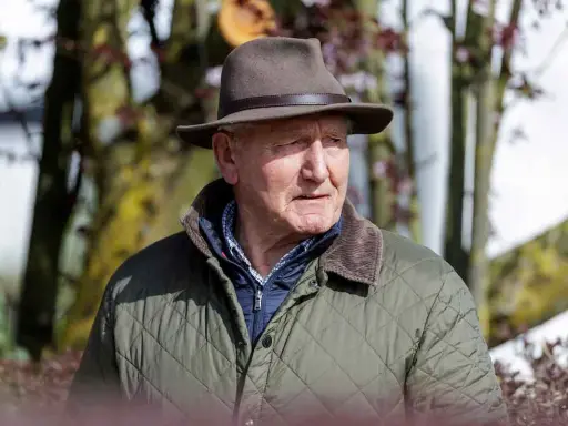 Klaus Balkenhol, ein älterer Herr mit Hut und Steppjacke, blickt nachdenklich in die Ferne.