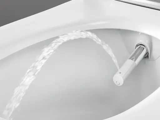 Chorro de agua saliendo de un inodoro moderno, mostrando la función de ducha integrada. Es como si el inodoro tuviera su propio bidet para quitar impurezas.
