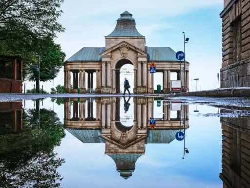 Odbicie zabytkowej budowli w kałuży, tworzące surrealistyczny widok. Nietypowe atrakcje Szczecin w deszczowy dzień.