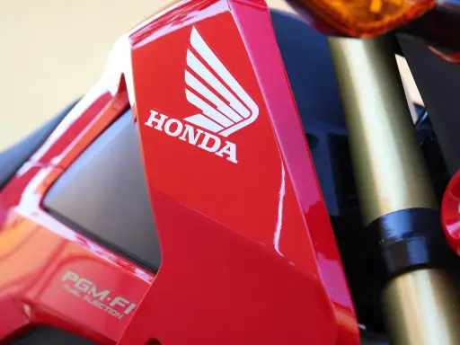 Czerwony motocykl Honda z logo i napisem PGM-FI. Pamiętaj o regularnych przeglądach motocykla 125!