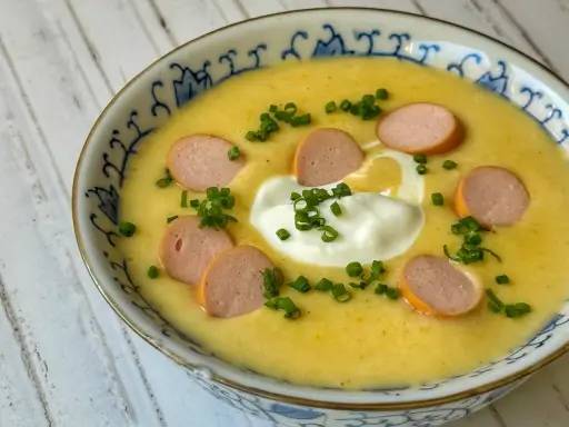 Cremige Kartoffelsuppe mit Würstchenscheiben, einem Klecks Sahne und Schnittlauch. Ein einfaches und leckeres Kartoffelsuppe Rezept für kalte Tage.