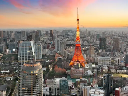 Widok na Tokio, największe miasto na świecie, z wieżą Tokyo Tower w pomarańczowych barwach o zachodzie słońca.