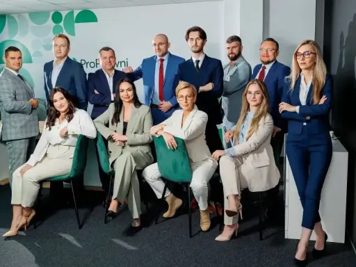 Zespół prawników w garniturach pozuje do zdjęcia w nowoczesnym biurze.