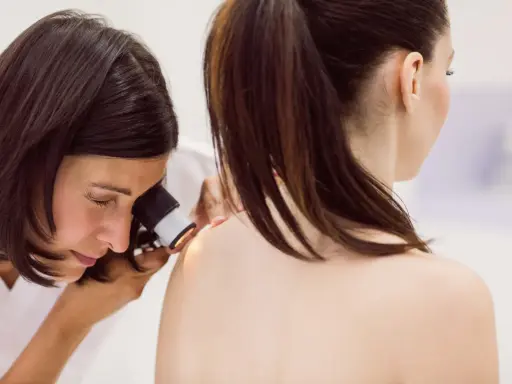 Lekarz od skóry bada znamiona pacjentki dermatoskopem.