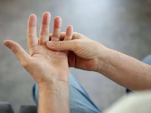 Eine Hand massiert die andere, um **Schmerzen in der Hand** zu lindern.