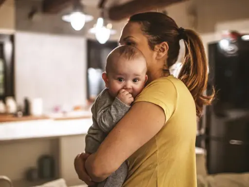 Zmęczona mama tuli dziecko, szukając sposobu, jak oduczyć dziecko jeść w nocy.