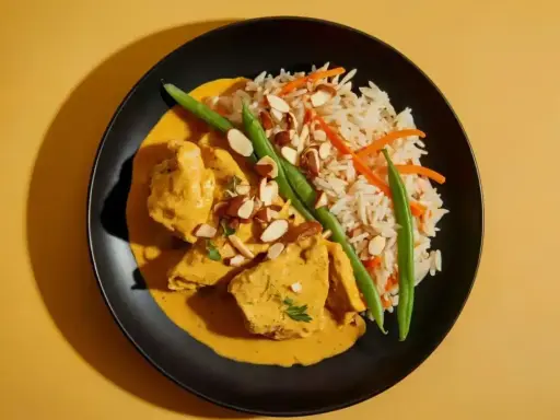 Aksamitny kurczak curry w kremowym sosie, podany z ryżem basmati, fasolką szparagową i płatkami migdałów.
