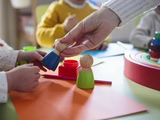Dzieci bawią się drewnianymi ludzikami. W żłobku od jakiego wieku można zapisać dziecko?