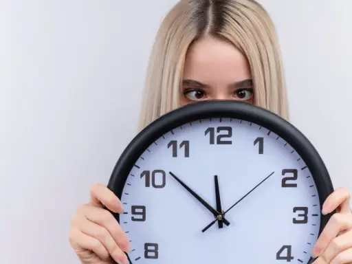 Dziewczyna z blond włosami ukrywa się za zegarem, patrząc zza niego. Czyżby czas miał dla niej jakieś szczególne 2233 znaczenie?