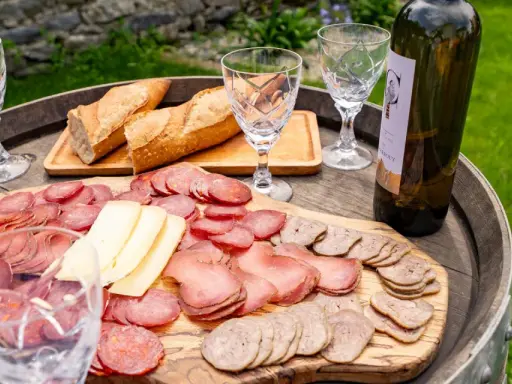 Plateau de charcuterie et fromage, pain frais, verres et bouteille de vin, une spécialité culinaire des Pyrénées.