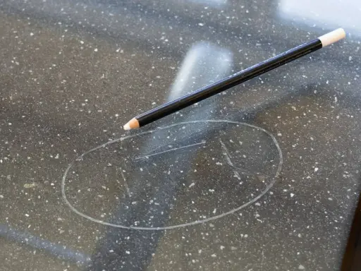 Ołówek na ciemnym blacie z widocznym śladem po wosku. Dowiedz się, jak usunąć wosk ze szkła.