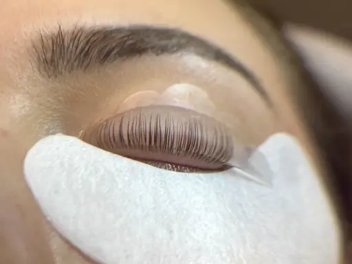 Un œil fermé, les cils recourbés sur un pad, prêts pour un allongement.
