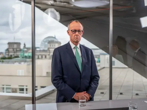 Mann im Anzug blickt nachdenklich, während im Hintergrund das Reichstagsgebäude zu sehen ist. Er spricht über die **Herausforderungen des Sozialstaats**.