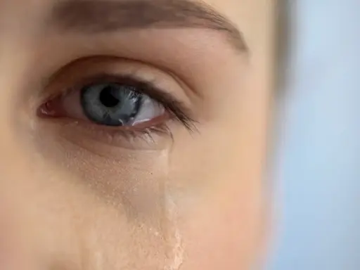 Zbliżenie na niebieskie oko, z którego spływa łza. Scena jak z filmu łzowego, pełna emocji.
