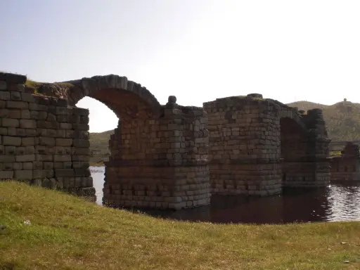 El imponente puente de Alconetar, con sus robustos arcos de piedra, se alza sobre las aguas, testigo de siglos de historia.