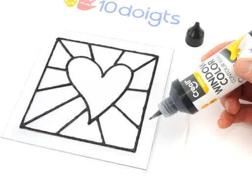 Main noire pour un modèle vitrail en forme de cœur. Un tube de peinture contour est tenu par une main.