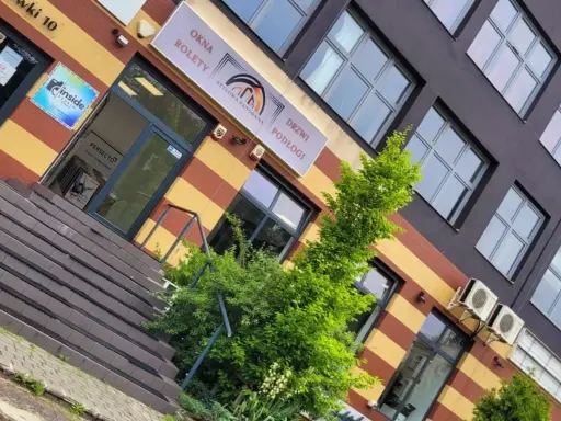 Elegancki budynek z oknami i drzwiami, z zielenią przed wejściem.