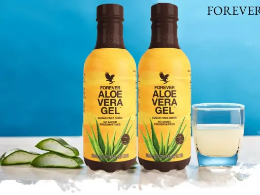 Dwa butelki napoju Forever Aloe Vera Gel, z widocznymi plastrami aloesu i szklanką napoju. Odkryj aloes właściwości.