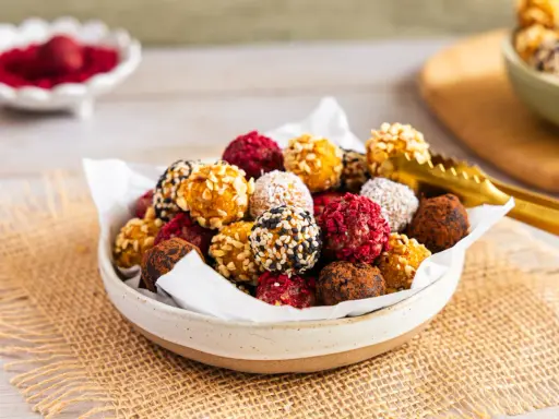 Schüssel voller bunter Energy Balls, perfekt für ein schnelles energy balls rezept. Mit Nüssen, Kokos, Kakao und Beeren verfeinert.