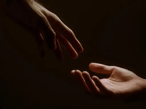 Due mani si sfiorano, un gesto che racchiude il significato di connessione, speranza e un nuovo inizio.