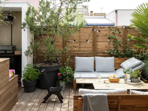 Aménagement terrasse avec pots : un coin salon cosy avec banquette, table basse, et verdure. Parfait pour se détendre.