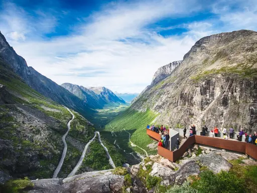 Besökare njuter av den dramatiska utsikten över Trollstigen i Åre, med en slingrande väg genom en grönskande dal.