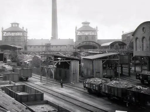 Ein Zeugnis der **hochindustrialisierung**: Zollverein II mit Schornstein, Loren voller Kohle und Holzlager.