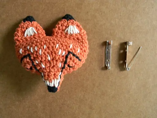Un adorable zorro naranja tejido a crochet, listo para convertirse en un broche. ¡Perfecto para quienes buscan patrones de broches crochet únicos!